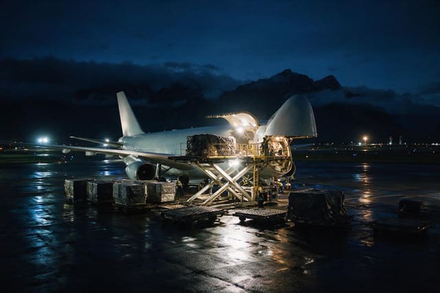 Avión de carga siendo estibado de noche en plataforma
